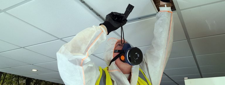 An asbestos surveyor looking in a ceiling voice for asbestos